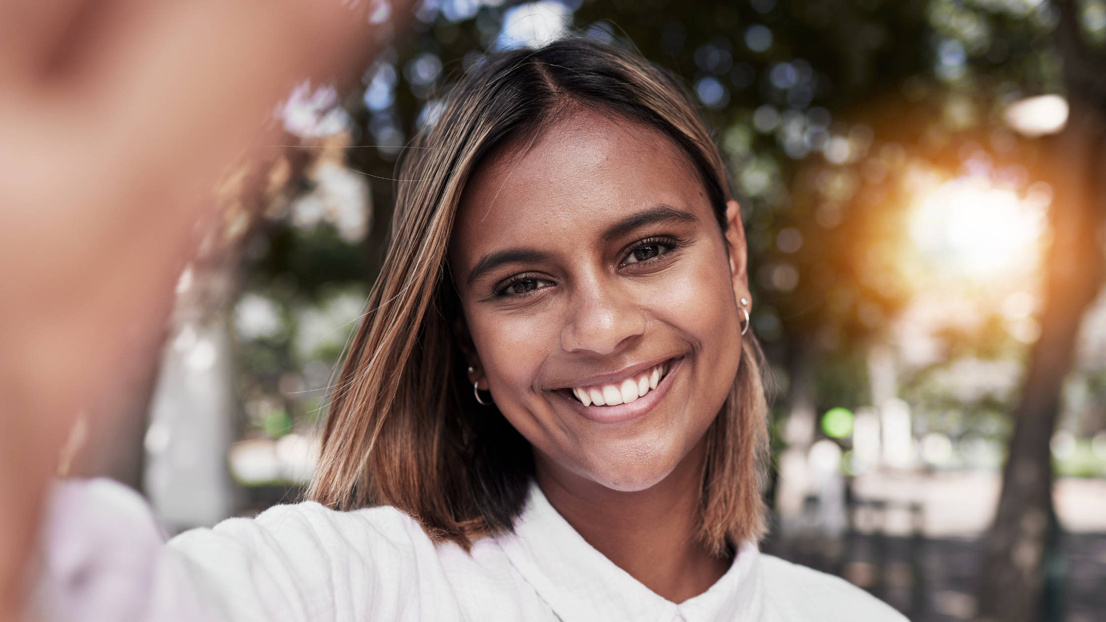 confident-healthy-smile-natural-light-firestone-co Woman smiling confidently outdoors, representing strong healthy teeth supported by proper mineral intake and preventive dental care