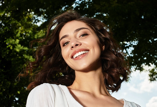 Smiling woman holding dental mirror in modern dental office setting