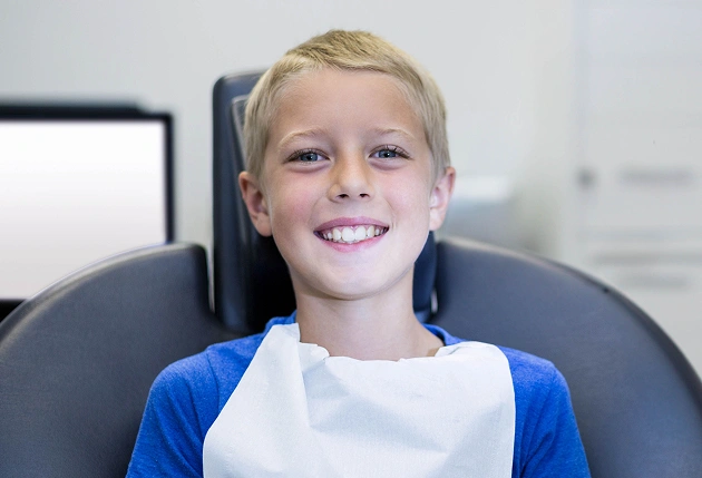 Young girl brushing teeth in dental office with turquoise chair in background