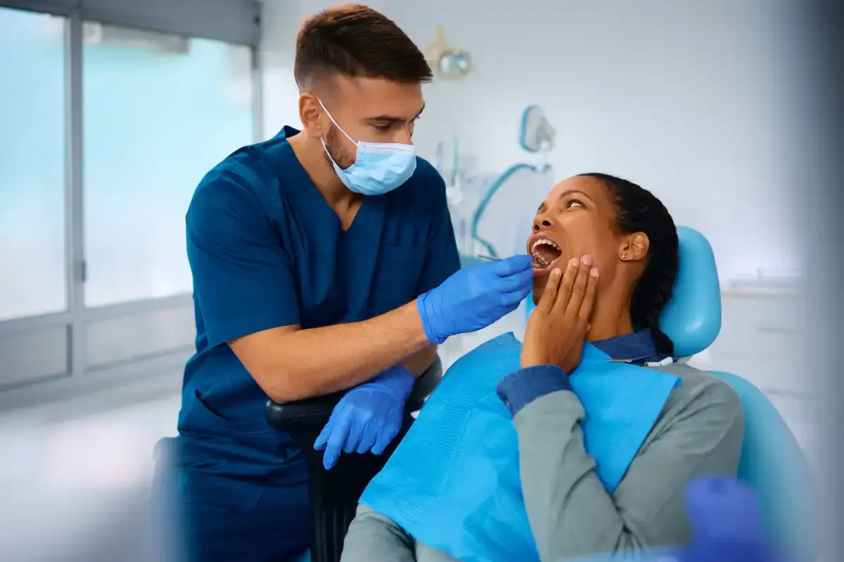 Dental Implant Dentist examining patient's mouth in dental chair during consultation for implant treatment.