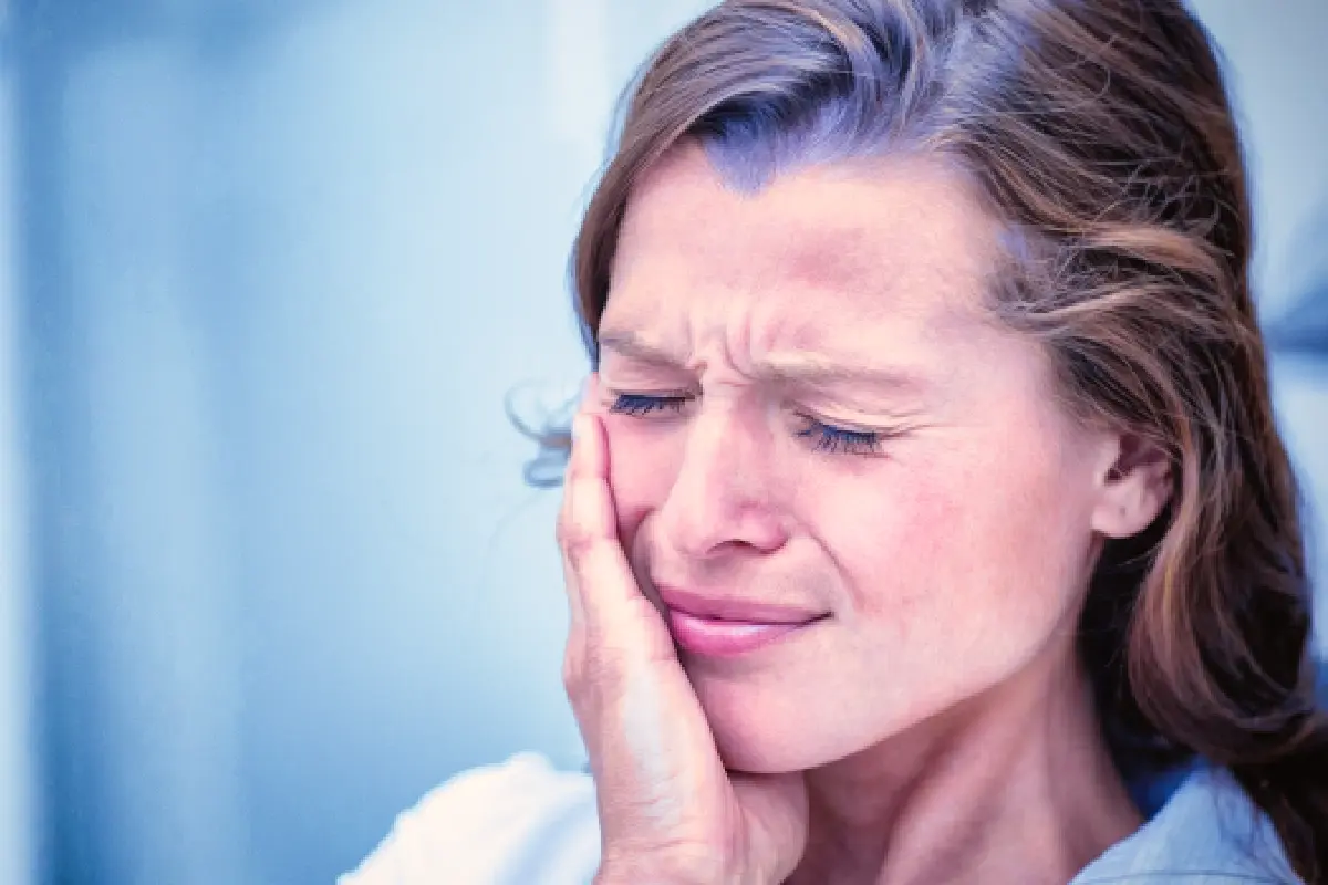 Sensitive tooth Woman holding her cheek in pain, experiencing tooth sensitivity after dental filling.