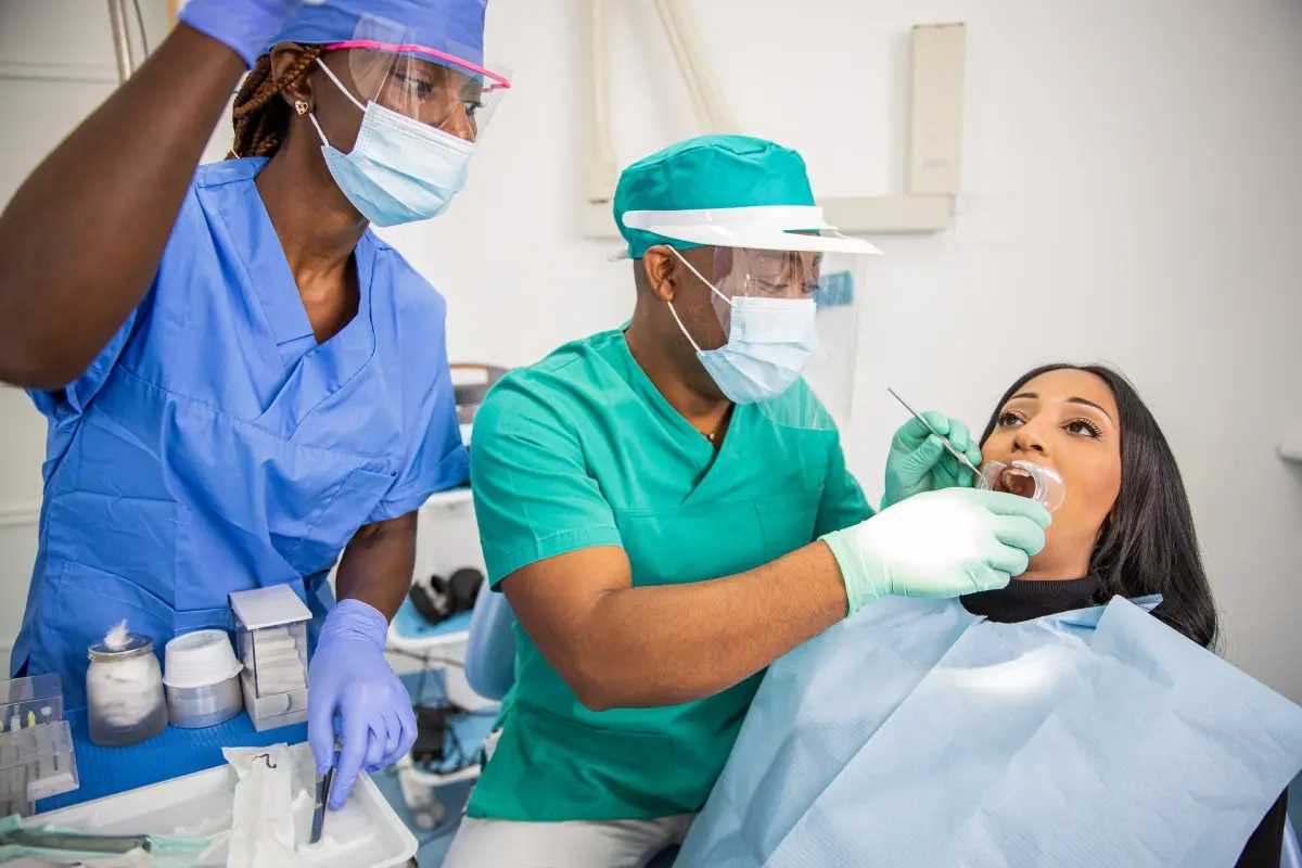 a-dentist-checks-a-patient-s-teeth-in-an-african Dentist examining patient's teeth during oral examination at Windsor dental practice.