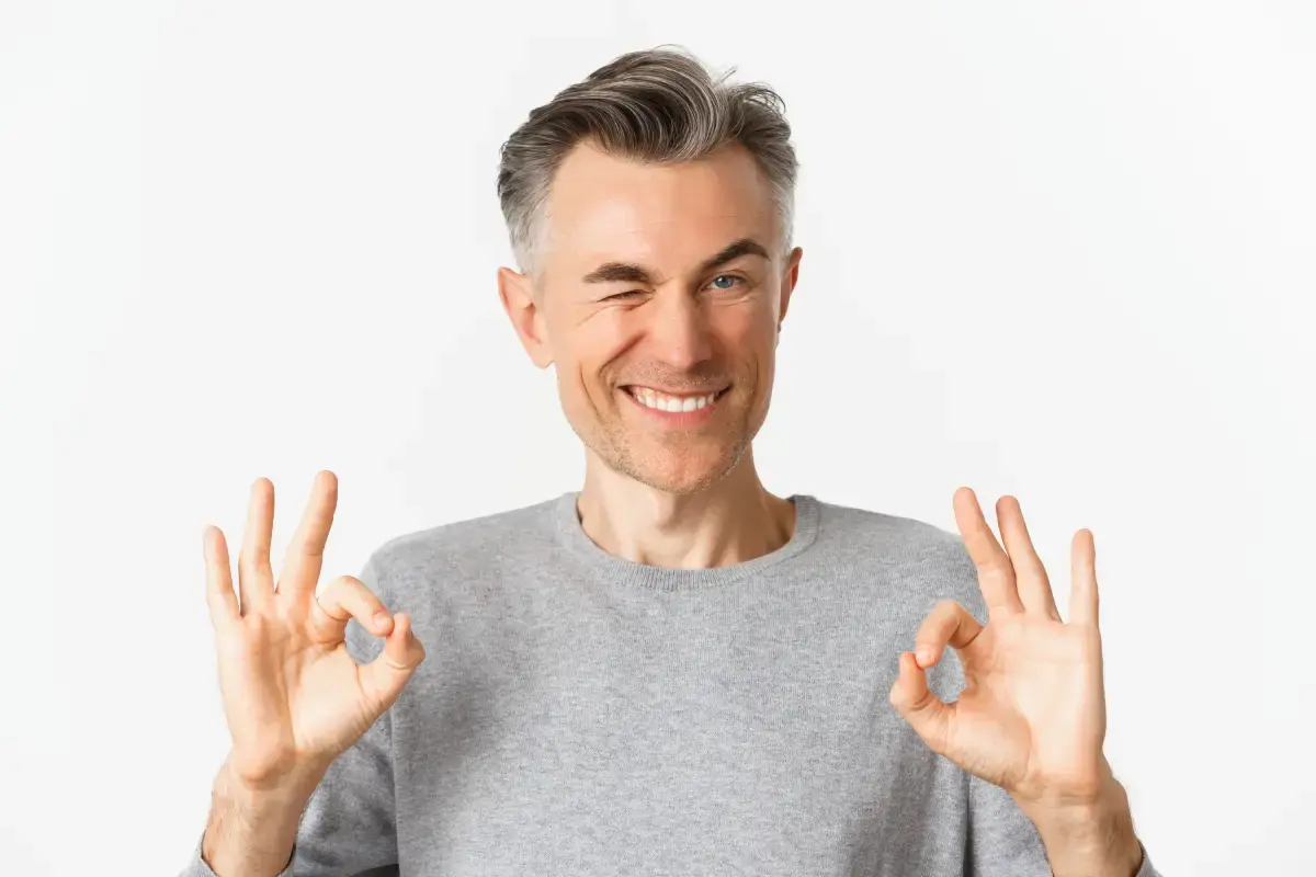 close-up-of-handsome-and-confident-middle-aged-man-2025-03-09-07-54-39-utc Man smiling and making okay gestures, representing satisfaction with dental implant results.